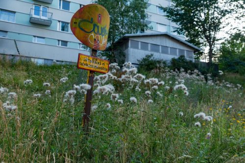 Niittyistä rinnettä ja vanha liikennemerkki Saarenkatu 6-8 pih